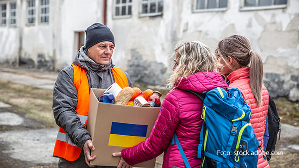 volunteer-in-orange-west-gives-a-box-of-food-donation-to-fleeing-refugees-from-ukraine