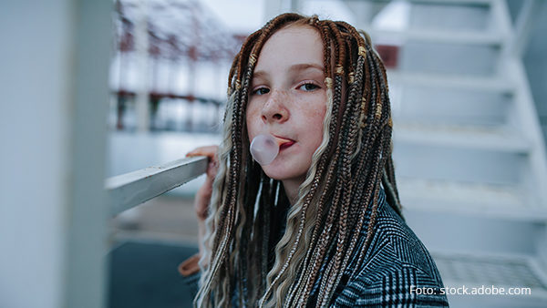 portrait-of-a-freckled-teenager-girl-with-dreads-making-a-gum-bubble