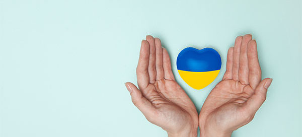 Helfende Hände umschließen ein Herz in den Farben der Ukraine