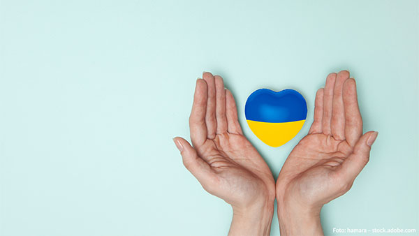 Helfende Hände umschließen ein Herz in den Farben der Ukraine